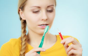 Young woman wearing orthodontic braces with toothbrush and proxy brush., 